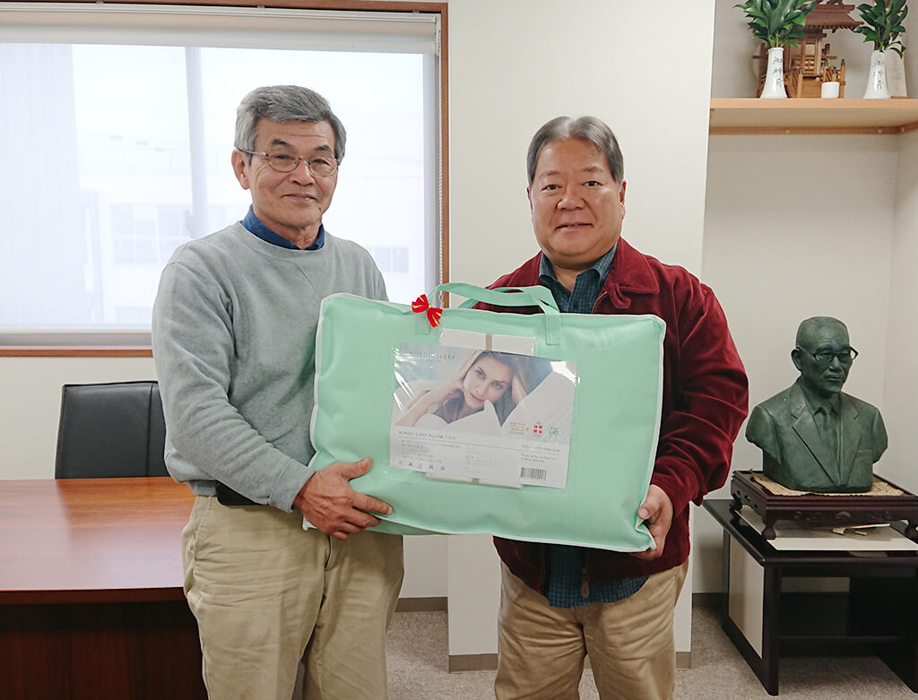 CEO Kondo (right) hands over a pillow